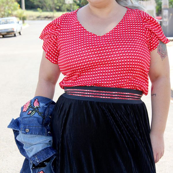 Look do dia plus size com blusa de corações e saia plissada