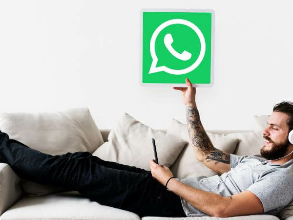 homem deitado no sofá segurando ícone do WhatsApp